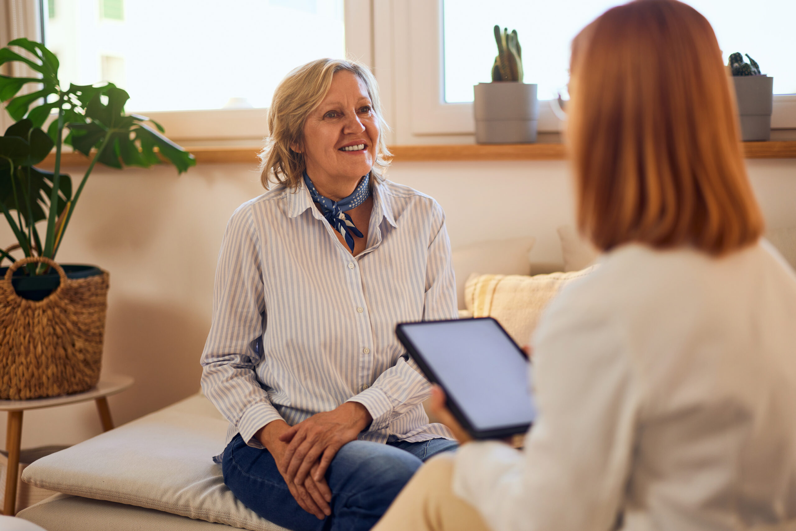 A smiling female patient talking to a female therapist, looking