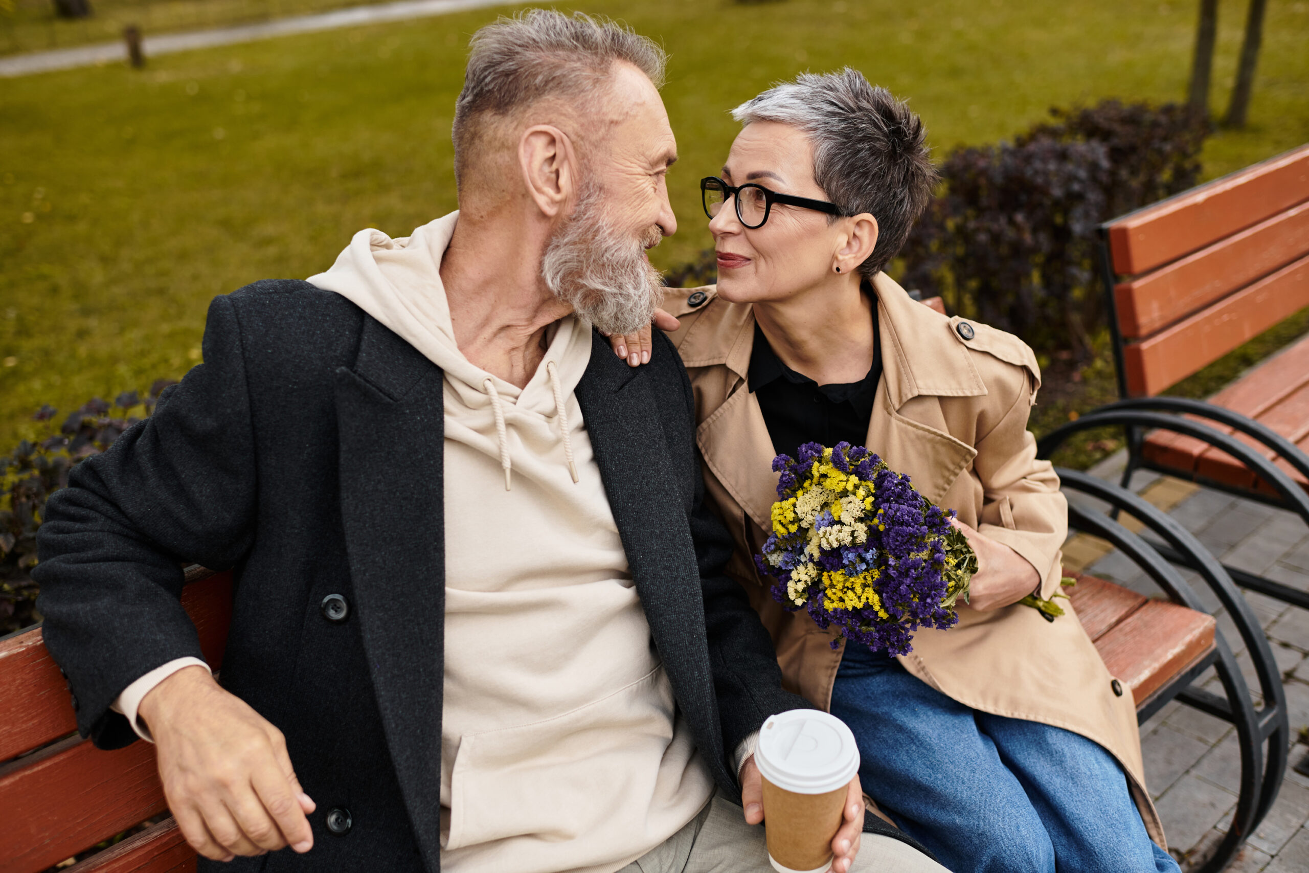 A mature couple enjoys each others company on a park bench, savo