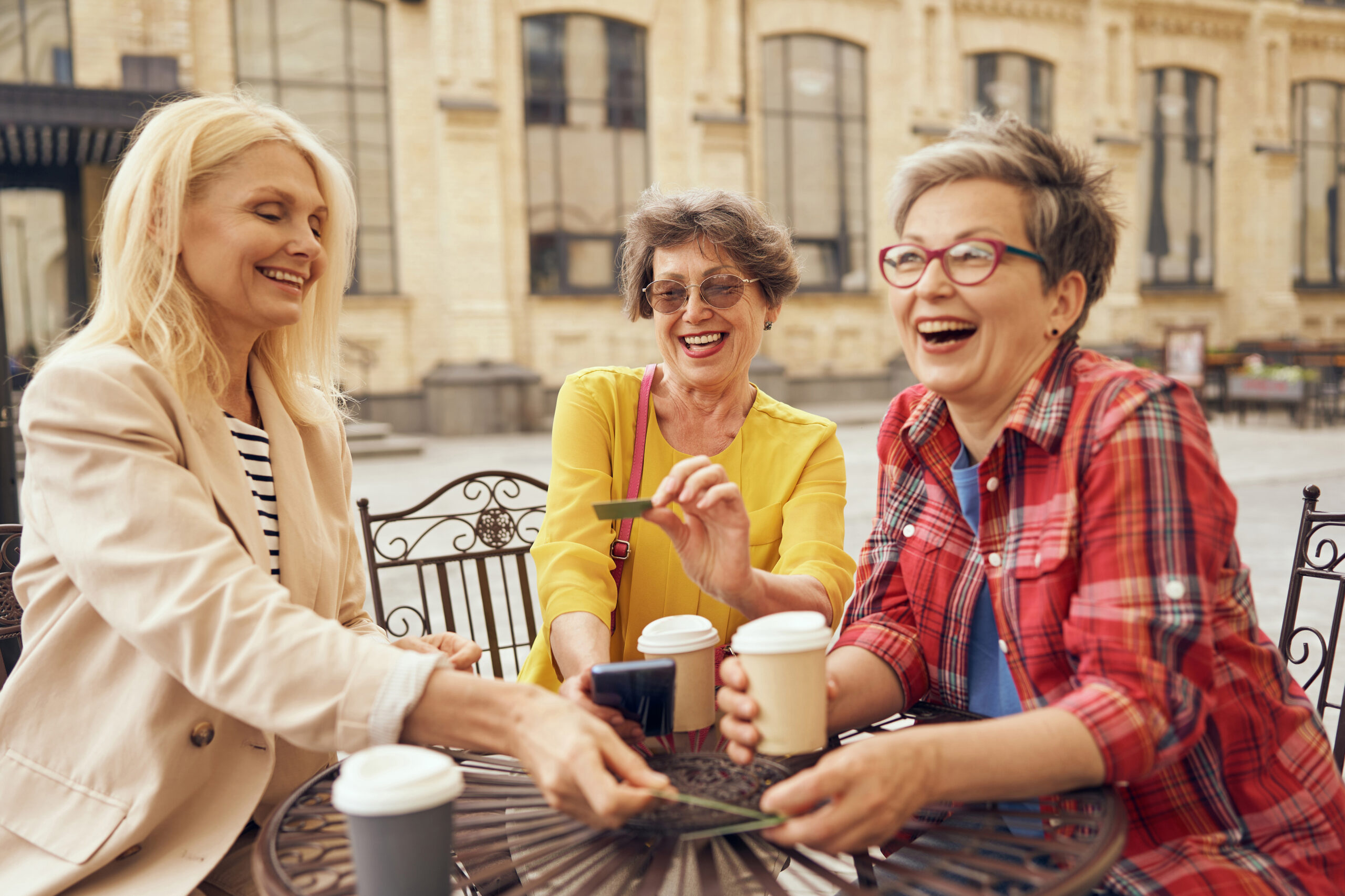 Mature women sitting in cafe, drinking coffee and laughing while enjoying spending time together