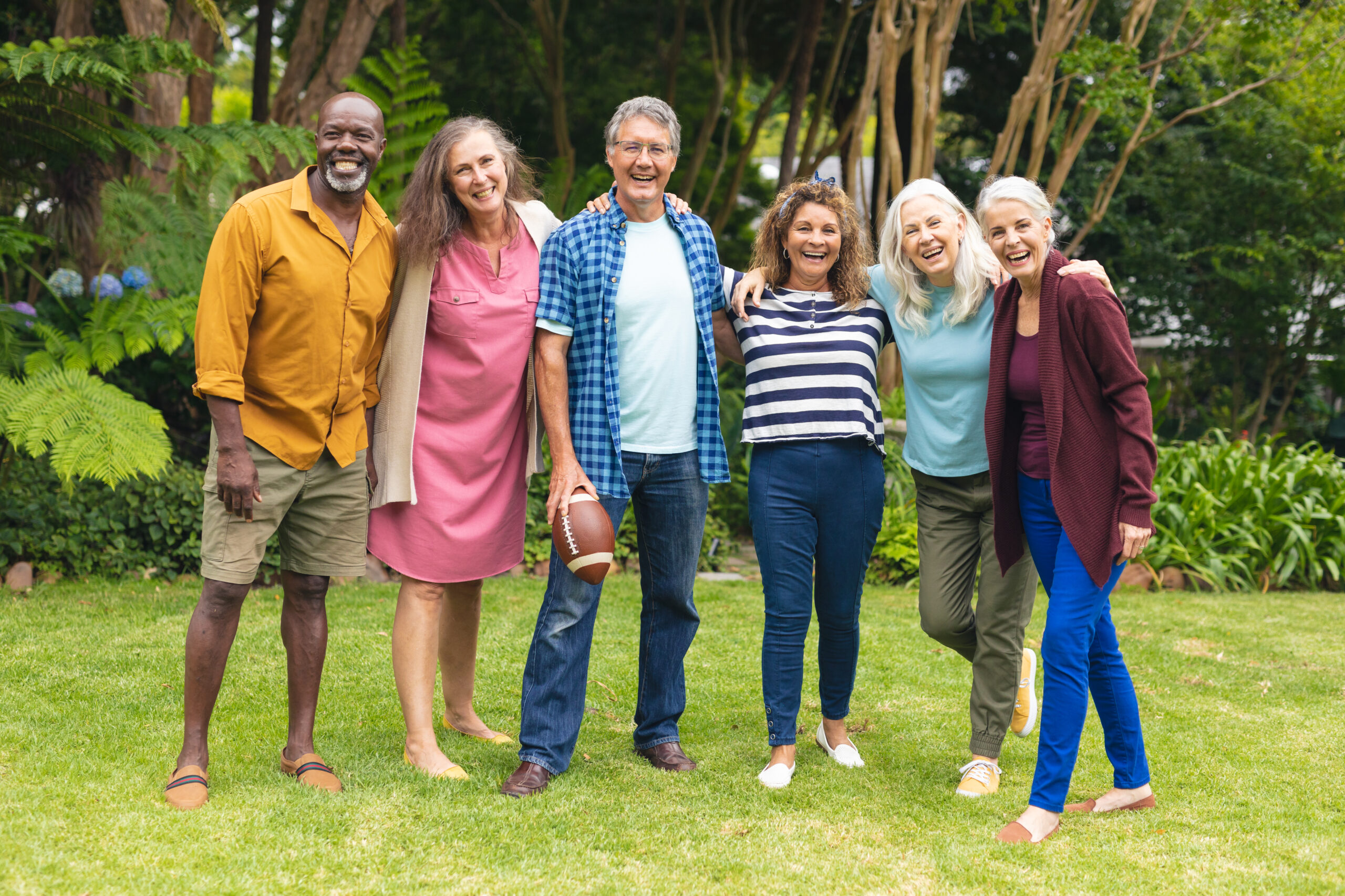Portrait of smiling multiracial senior male and female friends with arms around playing rugby. unaltered, lifestyle, friendship, leisure, sport and active